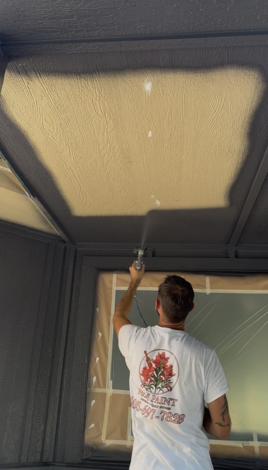 Spraying exterior paint on siding